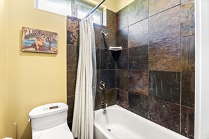 Family-friendly bathroom with a combination tub and shower, surrounded by rustic slate tiles.