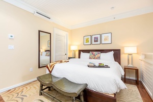 Stylish bedroom with a comfortable bed, soft lighting, and tropical accents.