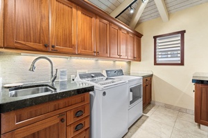Laundry room with dual machines, granite countertops, and ample cabinetry—ideal for long stays or large groups.