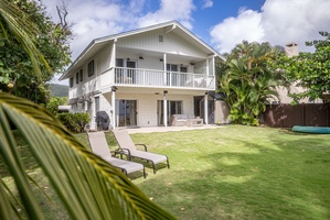 Charming view of the home from the backyard, with outdoor lounge chairs inviting guests to relax and enjoy sunny days.