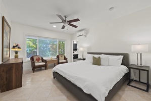 Guest bedroom with king bed and seating area, filled with natural light.