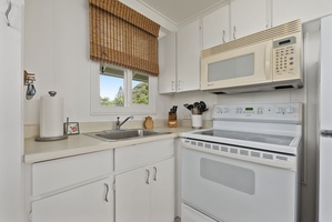 Your bright, fully-equipped kitchen awaits with modern appliances and charming bamboo blinds framing garden views.