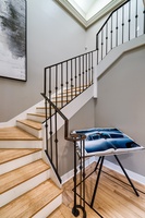 The main staircase leading to both primary suites and bedroom 1, with two queen beds.