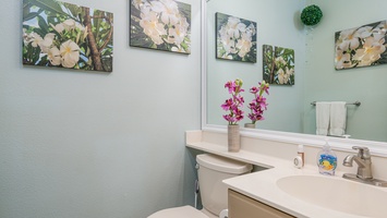 Refresh in your thoughtfully decorated bathroom featuring tropical artwork, fresh orchids, and modern amenities for your comfort.