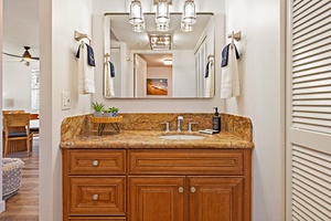 The bathroom at Mahana 1118 boasts granite counters, rich wood cabinetry, and modern fixtures.
