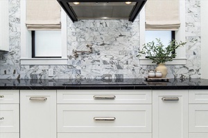 Detailed marble backsplash adds luxury and charm to the gourmet kitchen space.