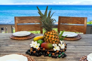 Tropical fruit centerpiece on the lanai dining table with ocean backdrop.