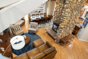 Relax in your spacious living area featuring a stunning stone fireplace, leather seating, and vaulted ceilings that create the perfect gathering space.