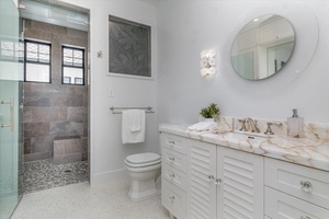 Beachy-modern bathroom with marble counters and walk-in shower.