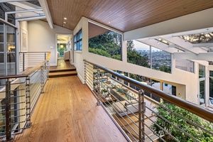 Upper walkway with vaulted ceiling and dramatic overlook of the great room and surrounding forest.