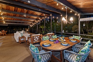 Your elegant outdoor dining terrace features tropical-inspired furnishings under twinkling lights, perfect for memorable evening meals surrounded by lush greenery.