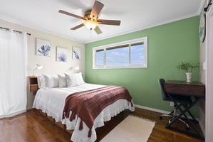 The primary bedroom offers a queen bed, ceiling fan, and peaceful green tones to help you unwind.