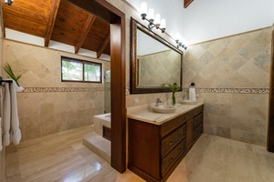 Luxurious ensuite bathroom with natural stone finishes and a large mirror.