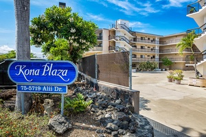 Kona Plaza property entrance with tropical landscaping and volcanic rock features welcomes guests to this Hawaiian destination.