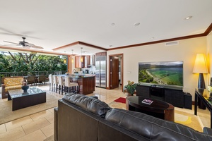 Unwind in your open-concept living space where lush tropical views and a modern kitchen blend seamlessly. Sink into the plush leather sofa and enjoy the natural light pouring in.