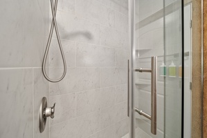 Walk-in shower with sleek tile and rainfall-style showerhead—refreshing after beach days.