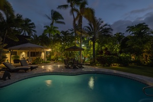 Tranquil poolside retreat illuminated for serene nighttime relaxation.