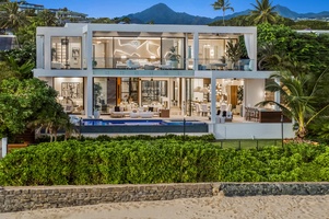 From the shoreline, admire the modern design of the residence framed by lush landscaping and ocean views.