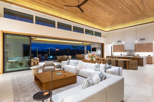 Sink into plush sofas beneath soaring wood ceilings while your gourmet kitchen awaits nearby—perfect for entertaining with stunning twilight views.