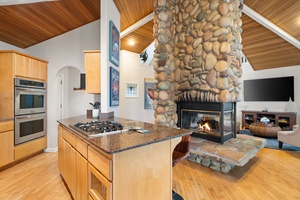 Your open-concept kitchen flows seamlessly into the cozy living area, where a stunning stone fireplace creates the perfect gathering spot for memorable evenings.