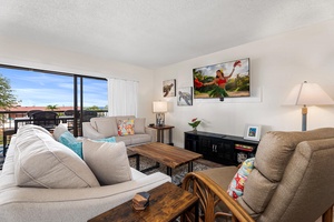 Relax in your bright living room with comfortable seating, tropical artwork, and stunning outdoor views through expansive windows.