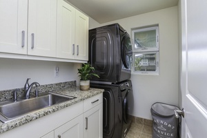Laundry room located on the second floor includes full-size washer and dryer alongside a convenient counter for organizing laundry, as well as a dedicated laundry sink.