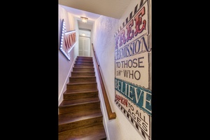 Stairway down to the lower level, where you will find the media room, two bedrooms and a half kitchen