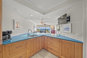 Prepare meals with a view in this fully equipped kitchen, featuring vibrant countertops and ocean vistas.