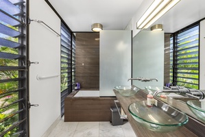 A spa-like bathroom with a soaking tub, sleek design, dual vessel sinks, and natural light.