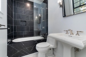 Bold contrast guest bath featuring dark tile and pedestal sink.