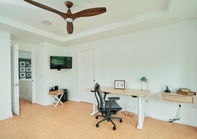 Focus and productivity flow naturally in your dedicated workspace, featuring an ergonomic desk, professional chair, and wall-mounted TV for comfortable remote work sessions.