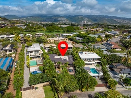 Aerial view of a tropical residential neighborhood nestled among lush green hills and mountains.