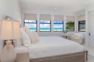 Guest suite with ocean views, calming tones, and plush bedding.