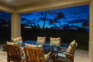 Covered lanai dining at sunset with tropical sky backdrop.