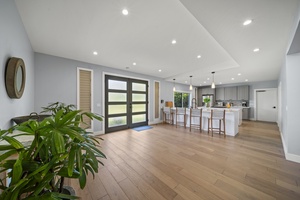 Spacious open-plan layout featuring clean lines, wood flooring, and natural light flowing through from the front door to the lanai.