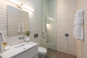 Stylish guest bathroom with textured walls glass enclosed walk in shower.