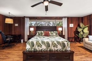 Sink into tropical comfort in your spacious bedroom with rich wood accents, a plush king bed dressed in botanical linens, and peaceful garden views streaming through the windows.
