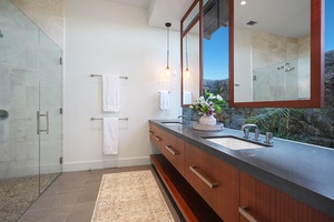 Bright bathroom featuring dual sinks and a glass-enclosed shower with a garden view.