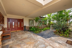 A covered entry framed by tropical greenery offers a quiet arrival into your island retreat.