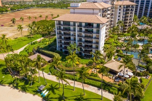 Stunning aerial view of beachfront resort buildings surrounded by tropical palm trees and manicured gardens in paradise.
