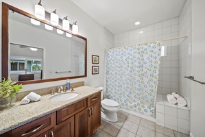 Private ensuite bathroom with shower/tub combo, granite vanity, and fresh design—adding convenience and comfort to this guest-friendly space.