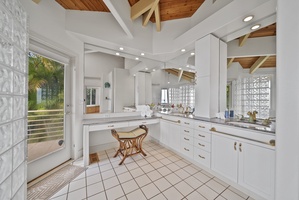 Pamper yourself in this spa-like bathroom featuring warm wood ceilings, marble countertops, and tropical garden views through glass doors.