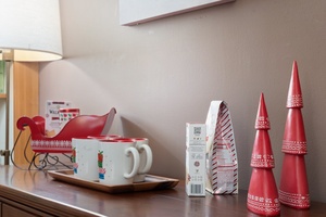 Festive holiday mugs and candy canes displayed on a wooden tray for a cozy winter treat.