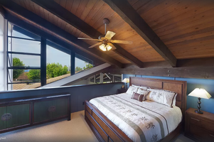 Loft bedroom features a California king bed, ceiling fan, and abundant natural light.