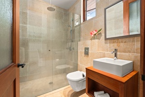 Pool bath with glass shower and stone tile.
