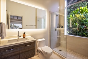 Elegant full bath with glass walk-in shower and garden views—modern and serene.