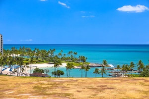A stunning tropical beachfront showcases pristine white sand, turquoise waters, and swaying palm trees under brilliant blue skies.