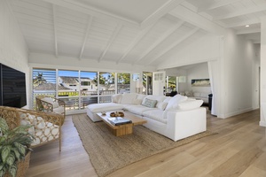 Coastal-chic living room features a spacious white sectional, natural textures, and large windows framing stunning ocean views.