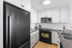 Sleek black-and-white kitchen setup with full-size appliances—ideal for prepping island meals or quick beach snacks.