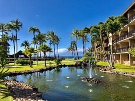A tranquil pond with a fountain enhances the tropical ambiance of the resort, offering peaceful surroundings and ocean views in the background.